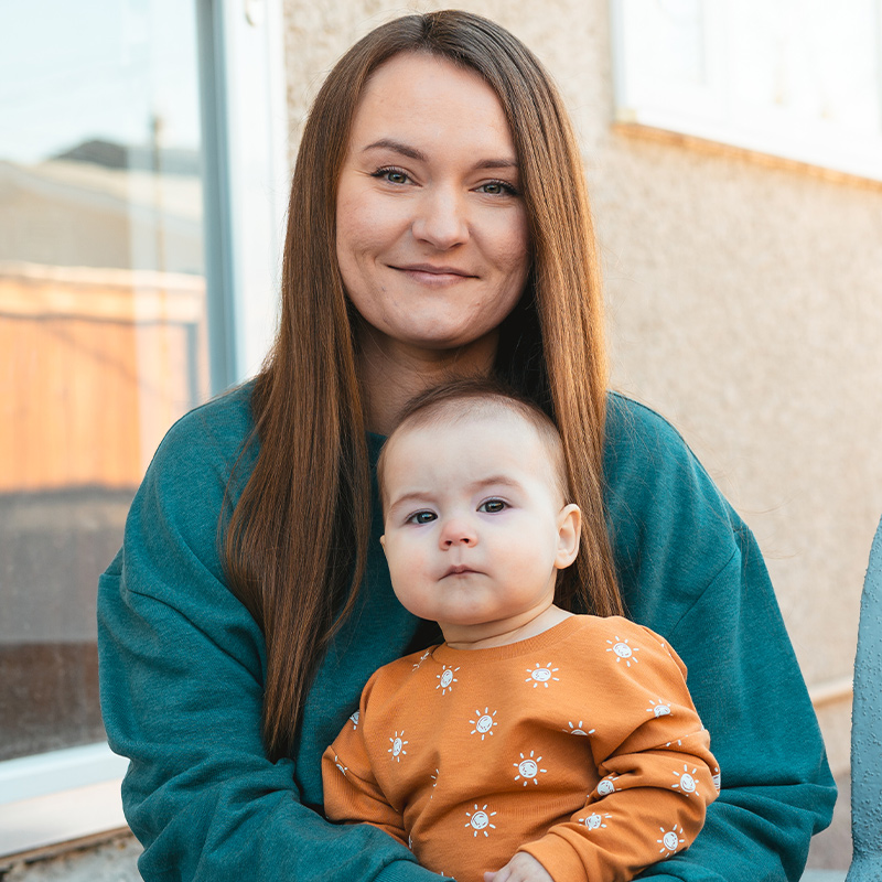 A mother holds her baby on her lap.