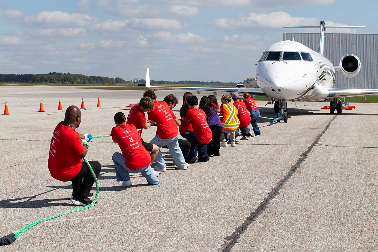 CAM students pull a private jet across the airport tarmac.