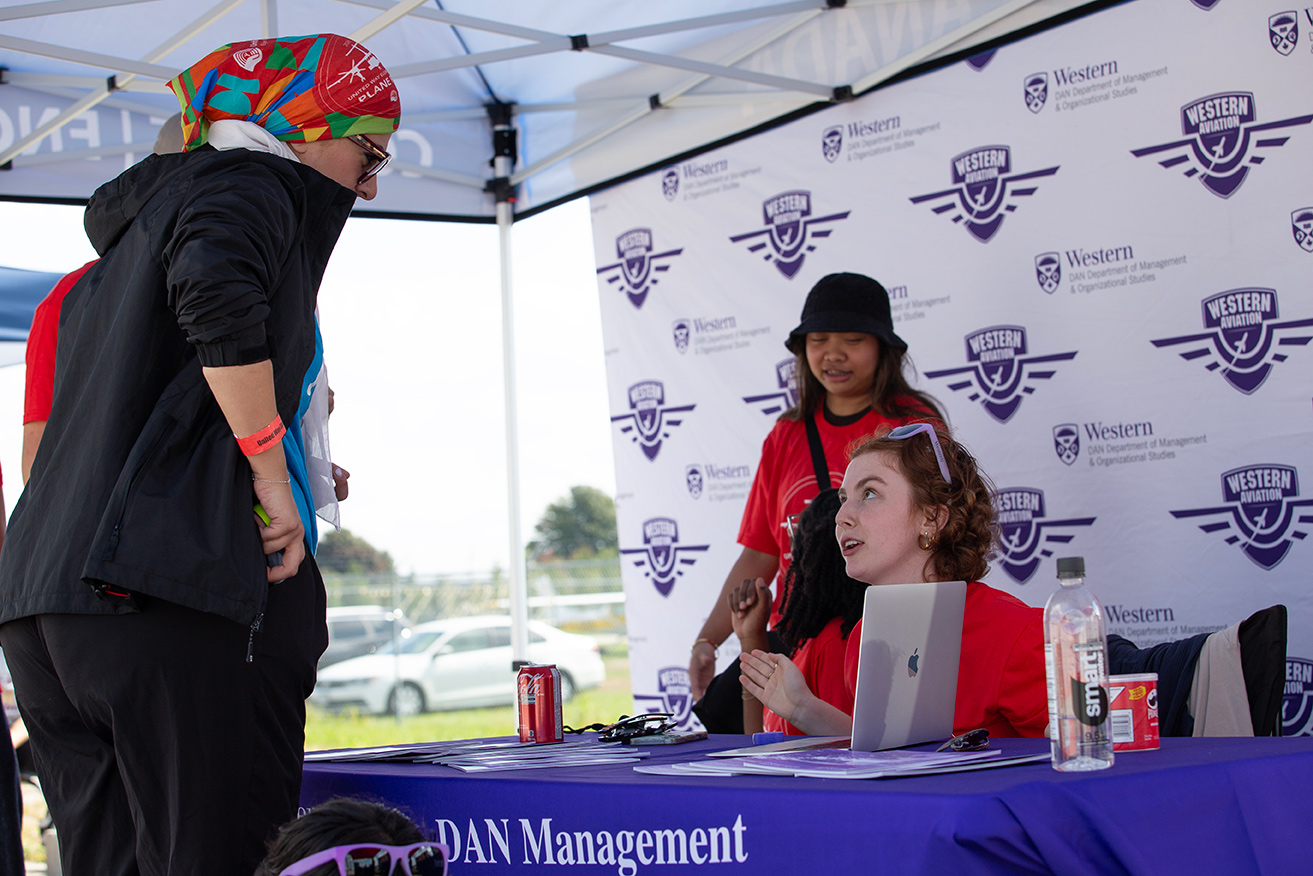 A CAM student answers questions at a booth.