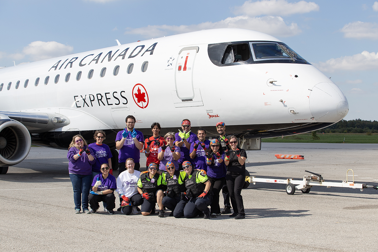 Western staff members pose in front of a large Air Canada plane.