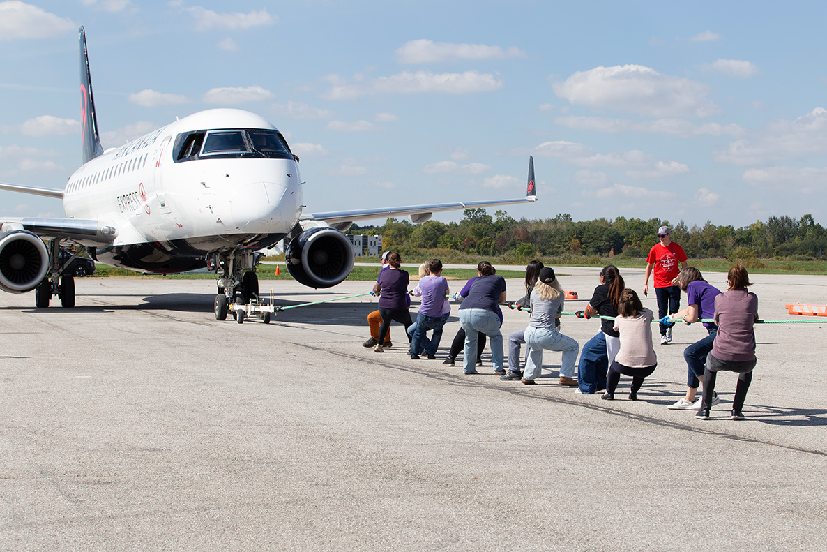 Western Research participants pull a large Air Canada plane.
