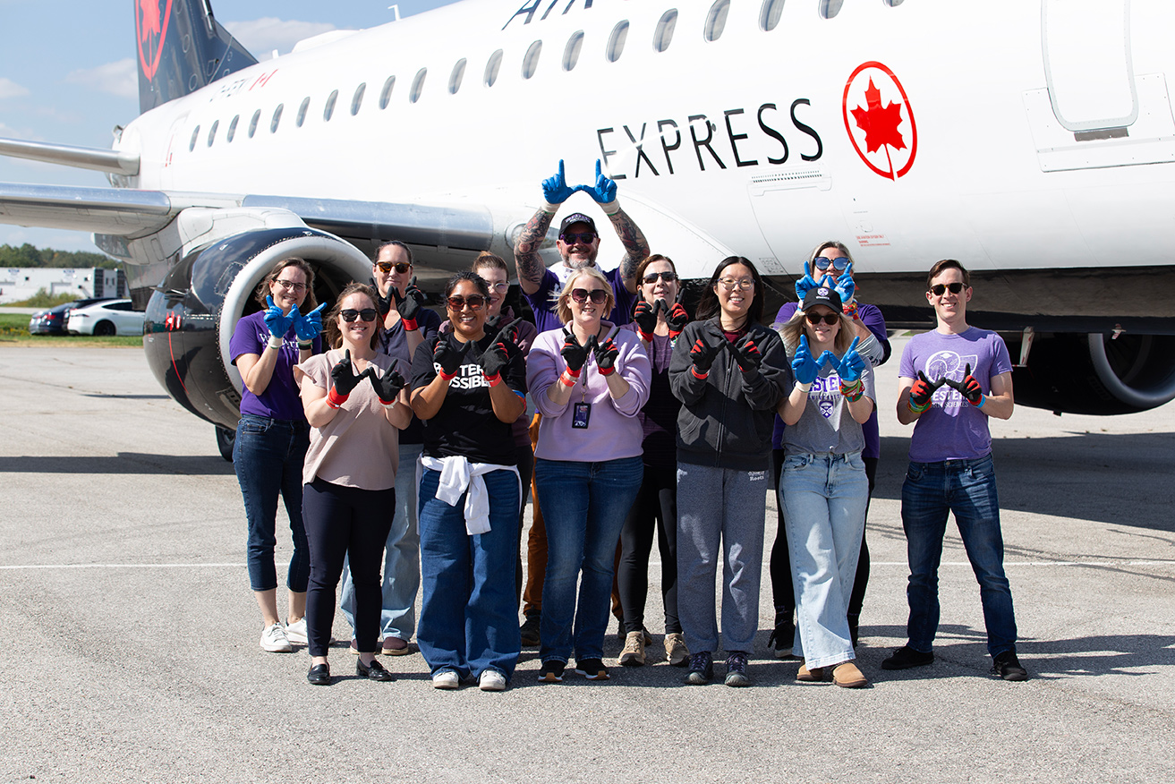 A team from Western Research pose in front of an Air Canada plane.