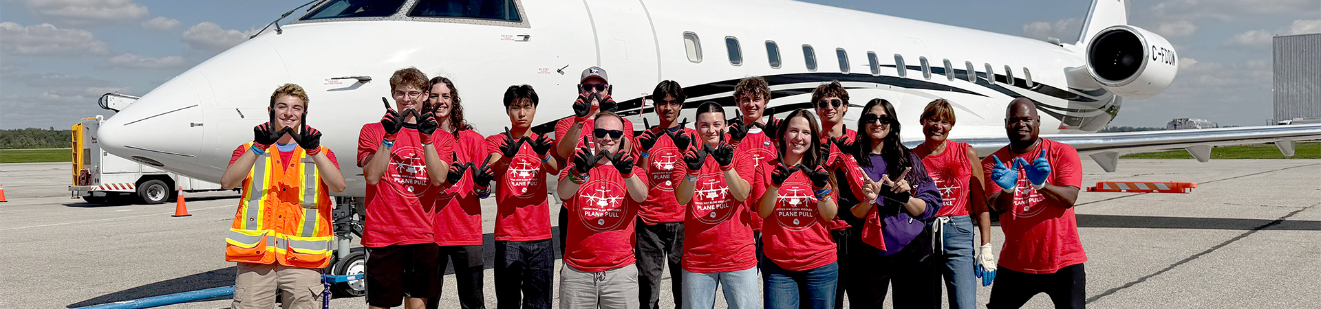 A group of Western commercial aviation management students stand in front of a private jet.